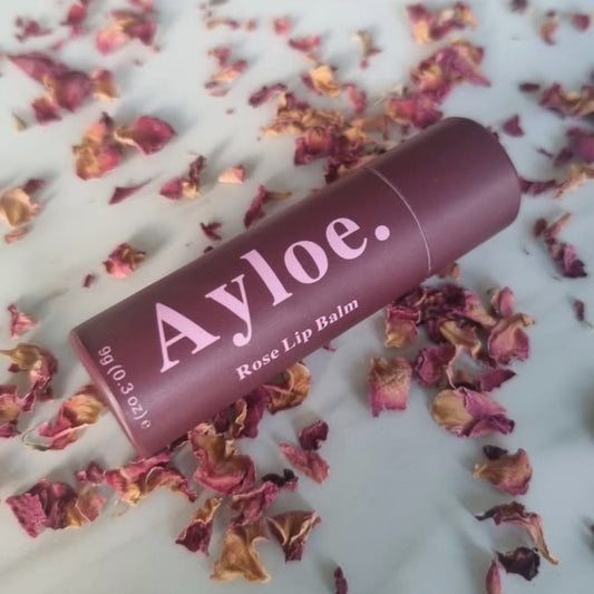 Ayloe rose lip balm on a white background with dried rose petals