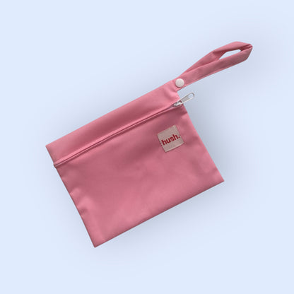 Pink wet bag with hush branding on light blue background