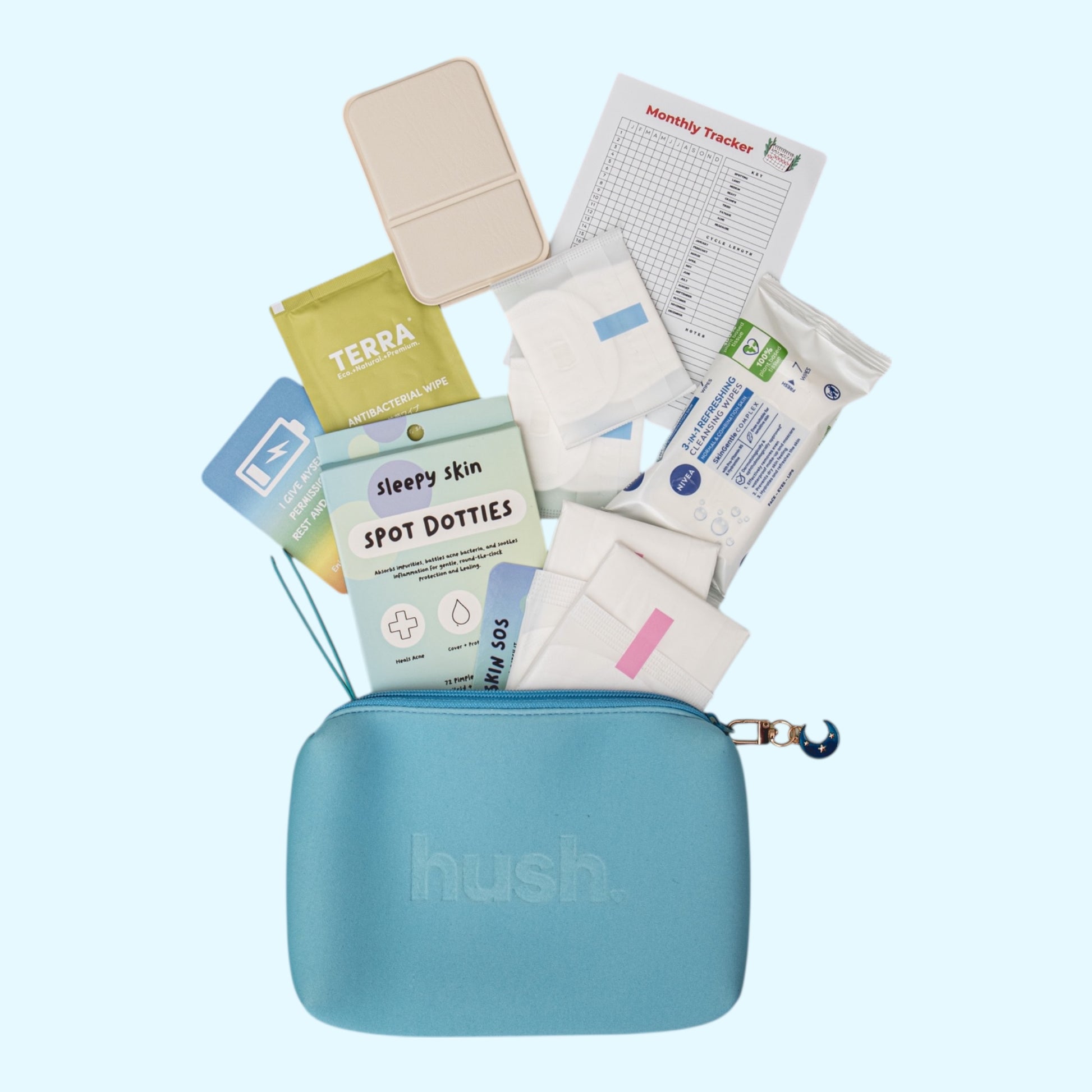 Blue hush pouch with sleepy skin pimple patches, pads, liners, wipes, mirror and tweezers sprawled out on a light blue background.