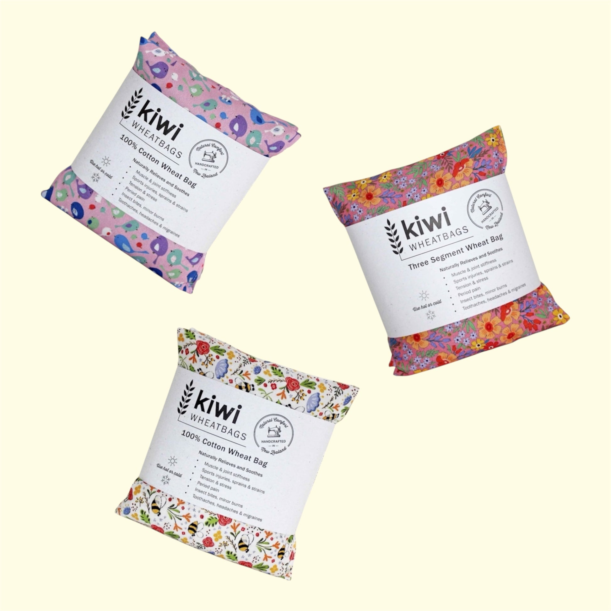 Three kiwi wheat bags in different floral and patterned paper packaging, arranged diagonally on a pale cream background. The white labels clearly show the brand 'kiwi WHEAT BAGS'.