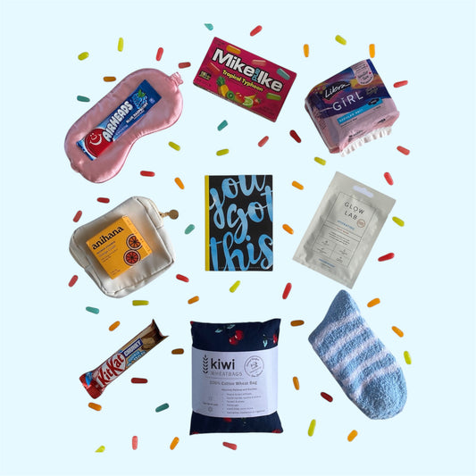 Contents of gift box on display. Eye mask, airheads candy, Mike and Ike candy, Libra girl pads, little purse, anihana shower steamer, you got this gratitude journal, glow lab face mask, kit kat, kiwi wheatbags and fluffy socks.