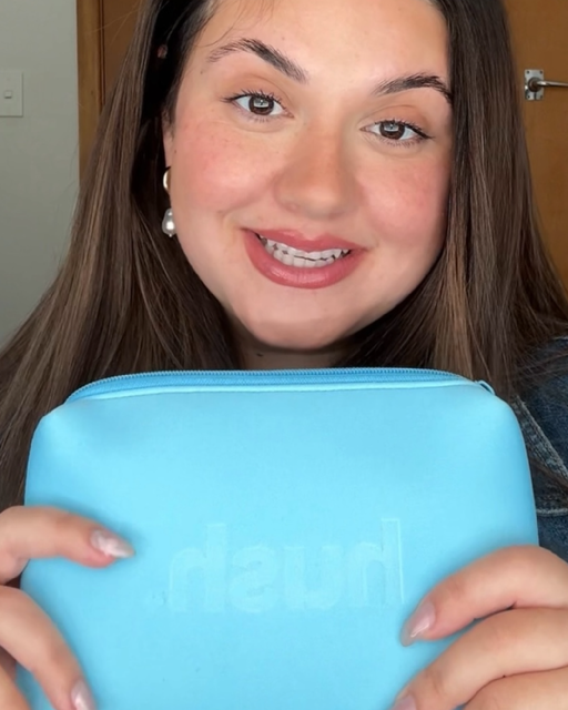 A lady holding a blue pouch with the hush logo embossed on it.